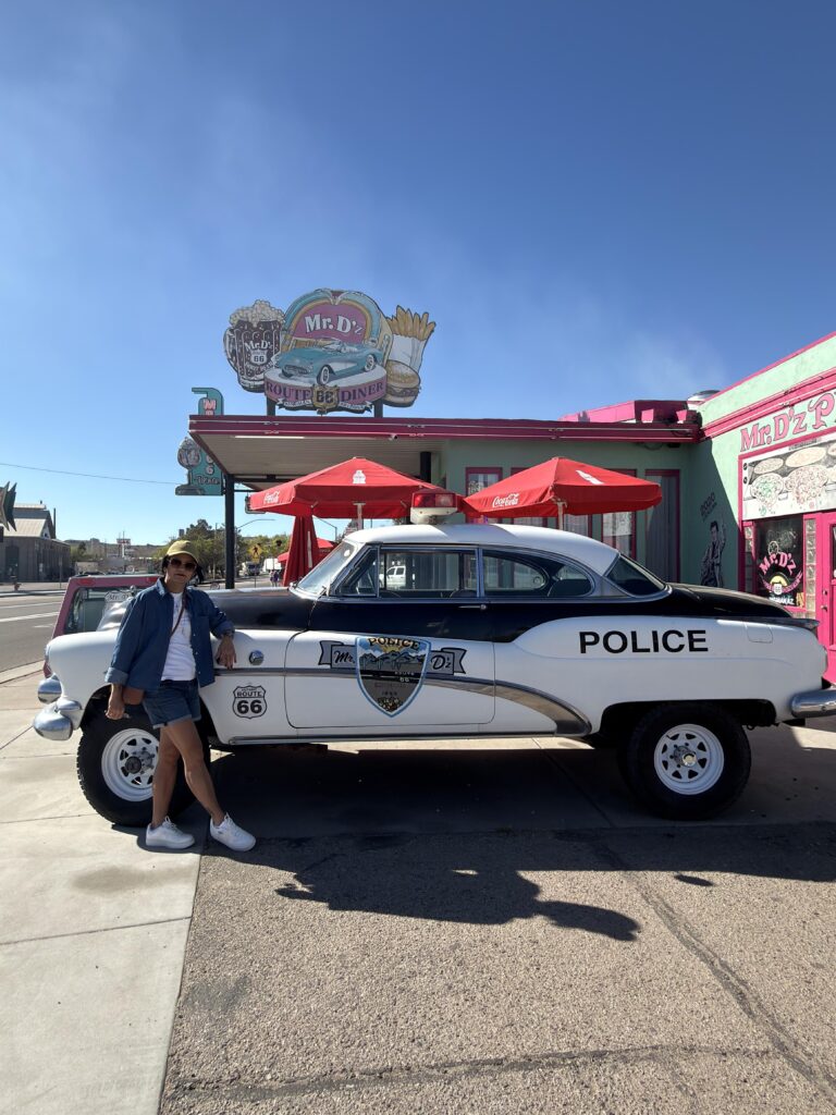 Frau lehnt an historischem Polizeiauto vor dem Mr. D'z Route 66 Diner in Kingman Arizona