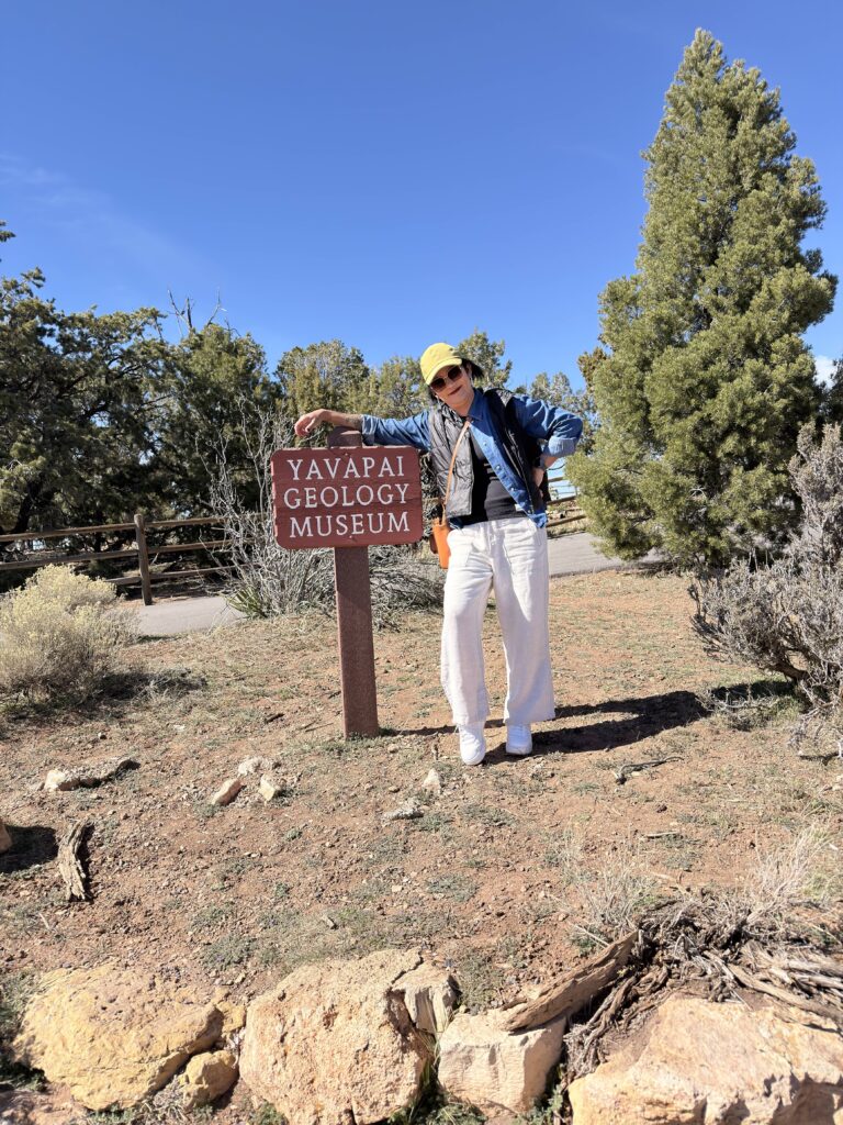 Frau lehnt am Schild des Yavapai Geology Museum am Grand Canyon South Rim