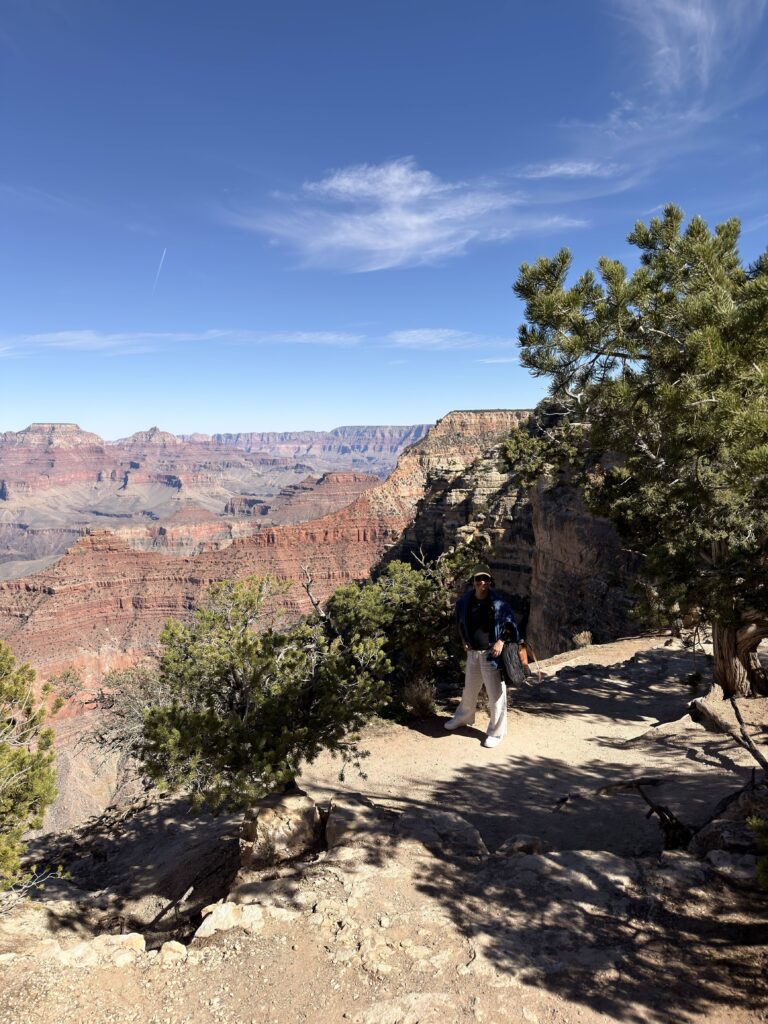 Frau auf dem Rim Trail am Grand Canyon South Rim mit weitem Blick über die roten Felsschichten