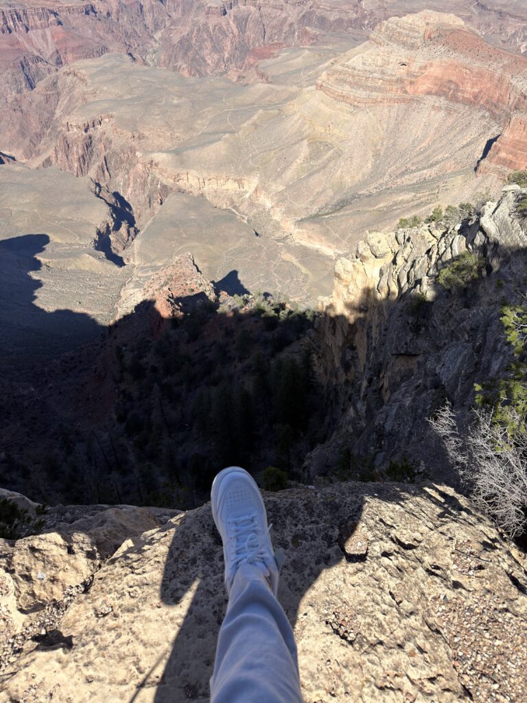 Bein baumelt über dem Abgrund des Grand Canyon South Rim mit Tiefblick in den Canyon