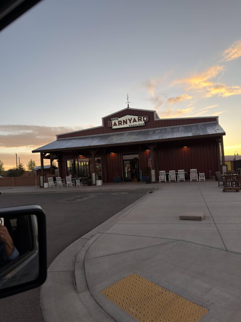 Außenansicht des Restaurants „The Barnyard – Food & Fun" in Page, Arizona bei Sonnenuntergang, mit weißen Schaukelstühlen vor dem Eingang.