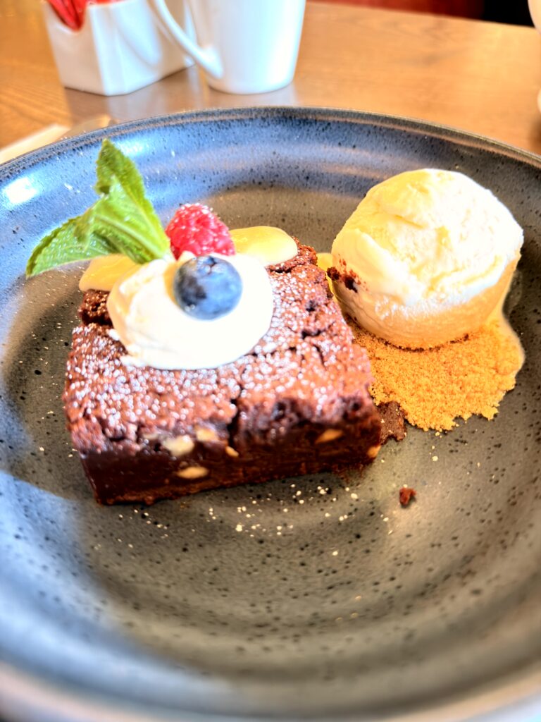 Schokoladenbrownie mit Puderzucker, Blaubeere, Himbeere, Schlagsahne und Vanilleeis auf Kekskrümel im Riu Plaza The Gresham Dublin