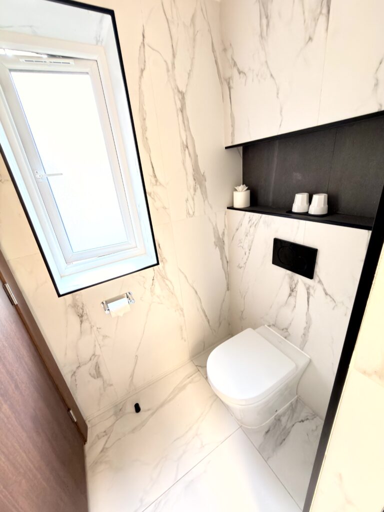 Modernes WC mit weißen Marmorwänden und schwarzer Designnische im Badezimmer des Riu Plaza The Gresham Dublin