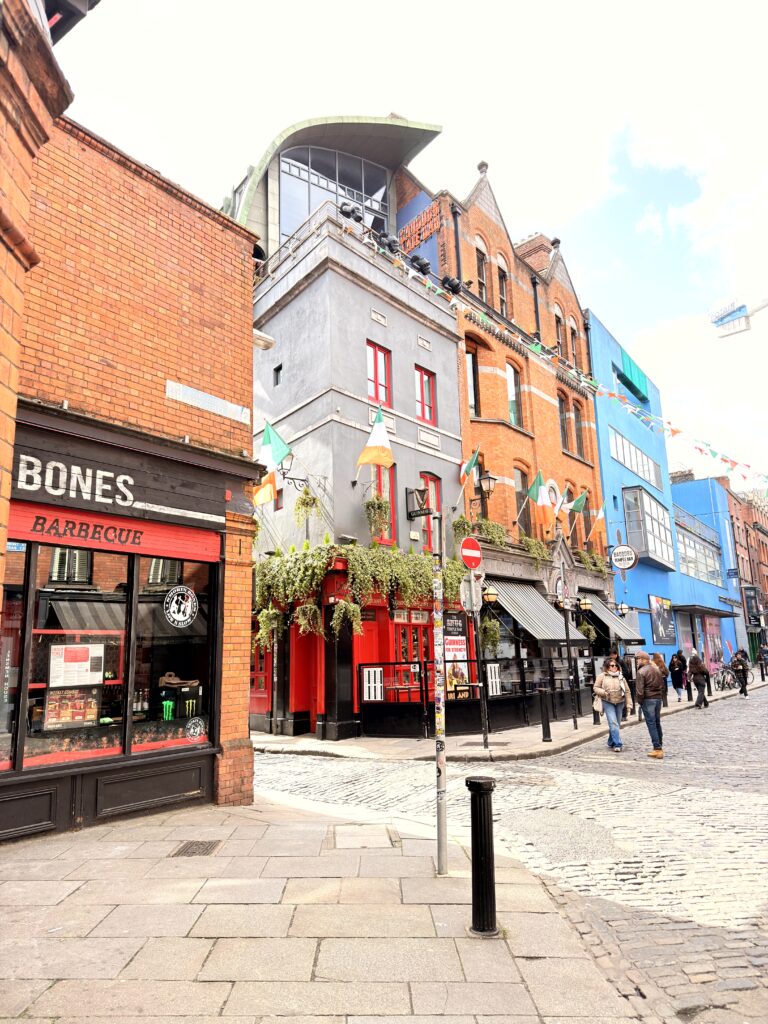 Kopfsteinpflastergasse im Temple Bar Viertel Dublin mit bunten Häusern und irischen Flaggen
