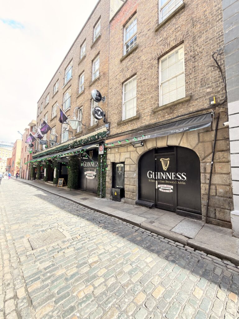Guinness-Pub mit schwarzer Fassade und Harfen-Logo an einer Kopfsteinpflastergasse im Temple Bar Viertel Dublin