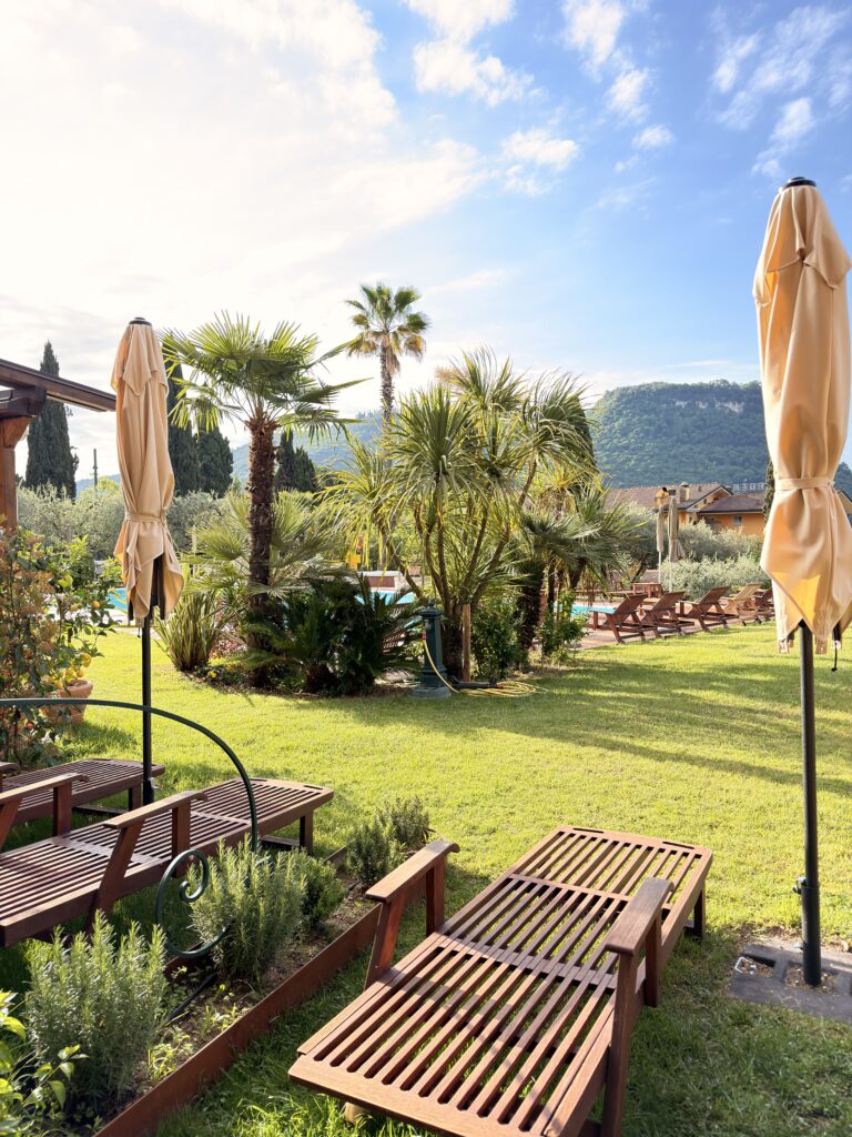 Hotelpool des Hotel Villa Madrina in Garda mit mediterraner Gartenanlage, Palmen und Liegen