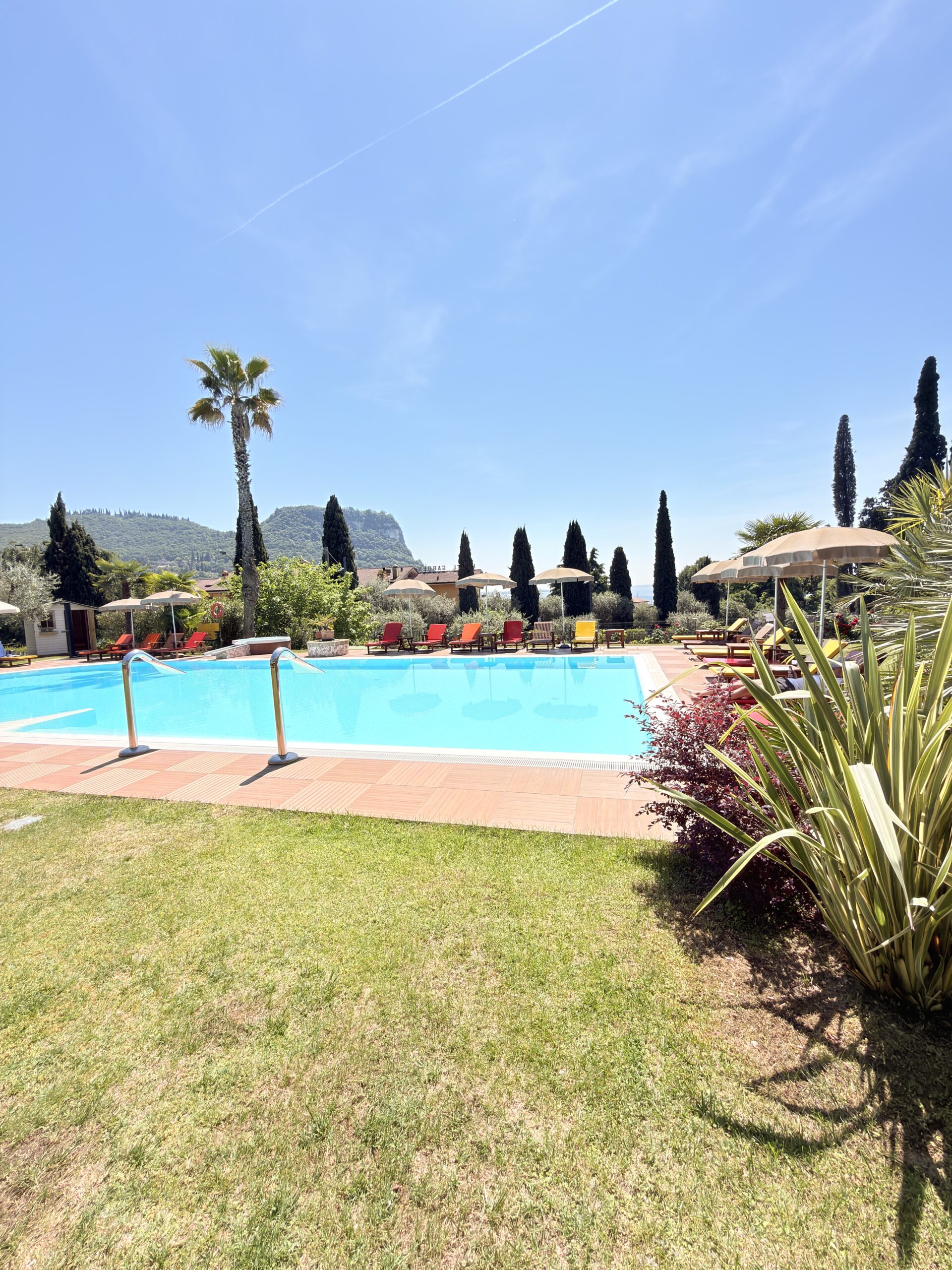 Außenpool des Hotel Villa Madrina in Garda am Gardasee mit Liegen und mediterraner Gartenanlage