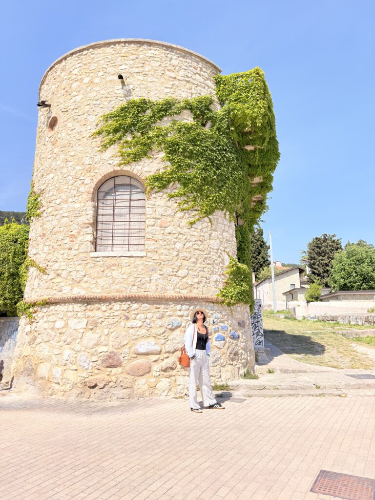 Ich lehne an der Wand des runden, mit Efeu bewachsenen mittelalterlichen Wehrturms Torre di Garda in der Ortschaft Garda am Gardasee