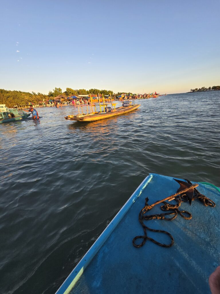 Bunte Holzboote auf dem Rio Maracaipe mit Besuchern am Ufer bei Abendsonne