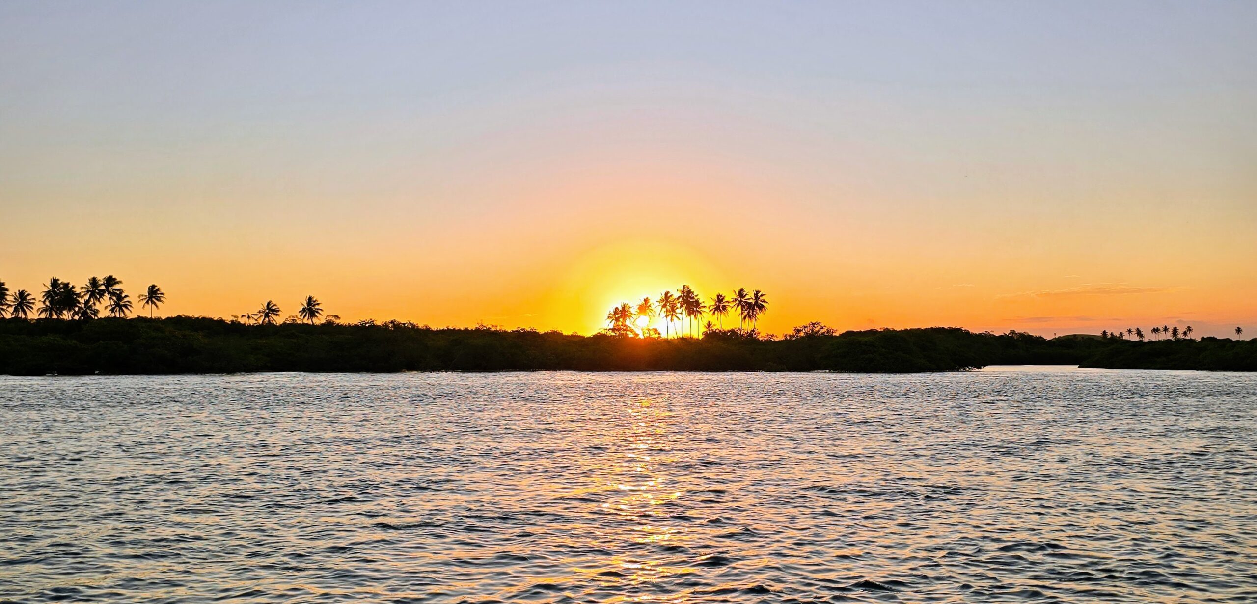 Panorama Sonnenuntergang am Pontal de Maracaípe – Sonne hinter Palmen spiegelt sich im Wasser