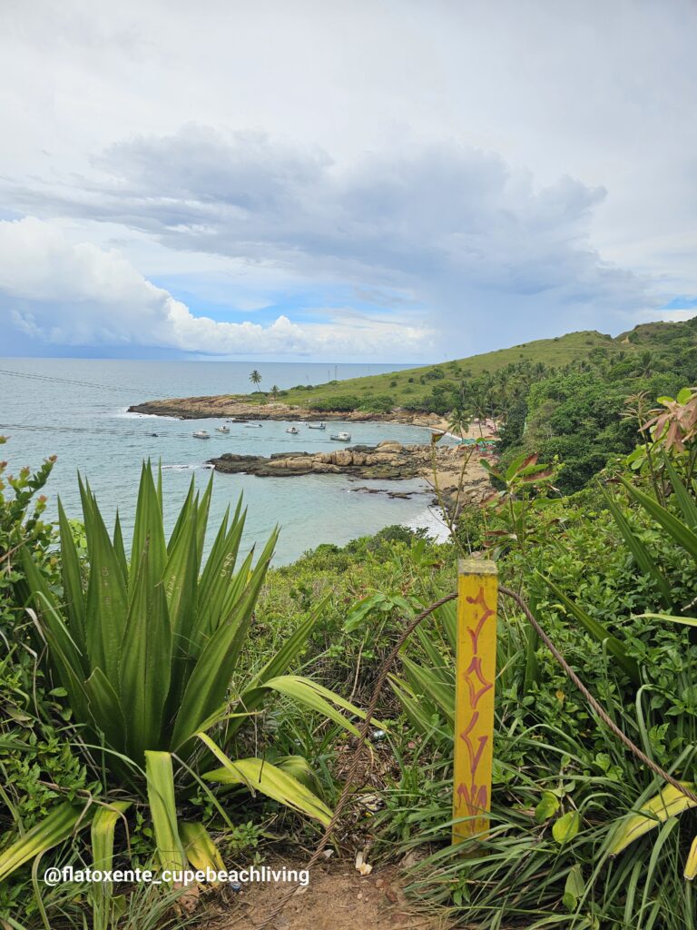Blick von einem grünen Hügel auf eine türkisfarbene Bucht mit Fischerbooten und Sandstrand bei Calhetas