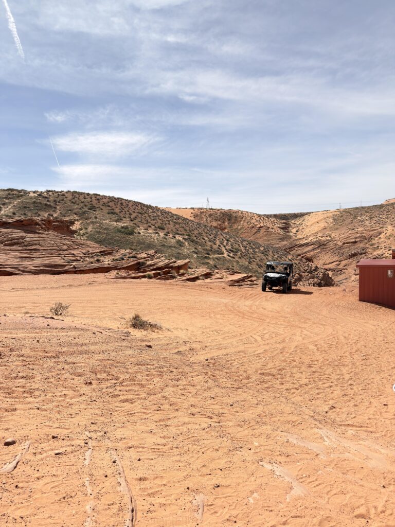 Geländewagen (UTV) am Eingangsbereich des Lower Antelope Canyon zwischen roten Sandsteinformationen