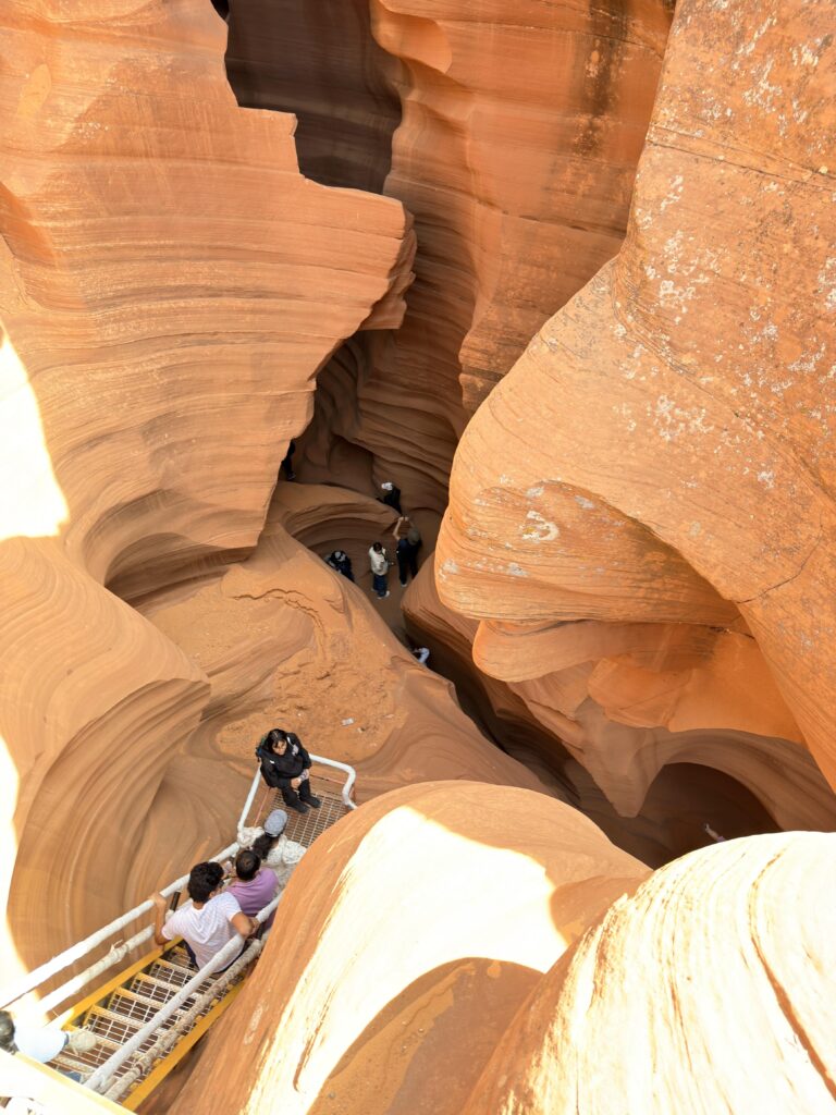 Blick von oben in den engen, gewundenen Slot Canyon des Lower Antelope Canyon mit Besuchern auf Stegen
