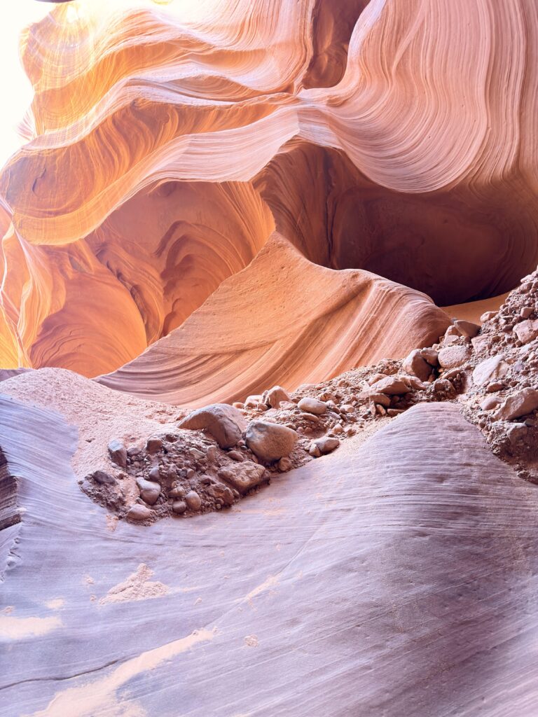 Steiniger Boden mit Geröll im Lower Antelope Canyon, im Hintergrund gewellte Sandsteinwände