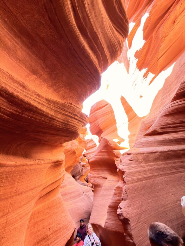 Weiter Blick in die gewundene Sandsteinschlucht des Lower Antelope Canyon mit Besuchern am unteren Bildrand