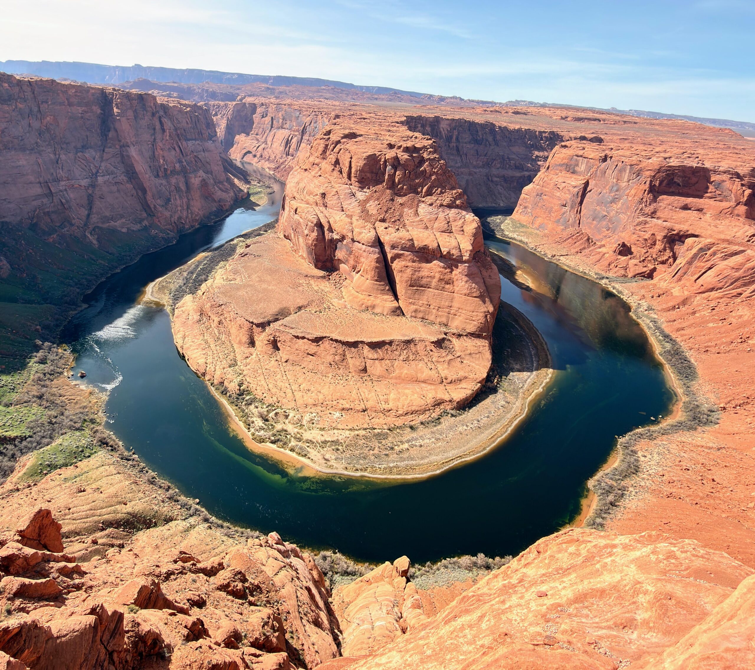 Blick von der Klippe auf die hufeisenförmige Flussbiegung des Colorado River am Horseshoe Bend, mit Fuß im Vordergrund