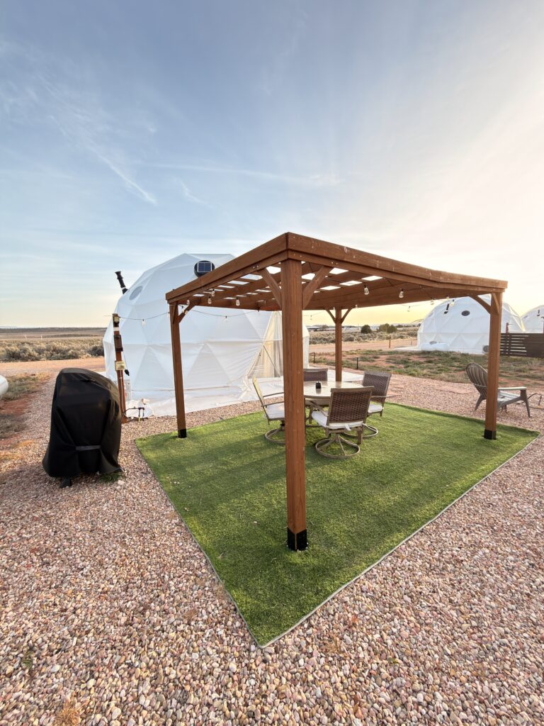 Überdachte Sitzecke mit Pergola, Grill und Kunstrasen vor Glamping-Zelten in Kanab