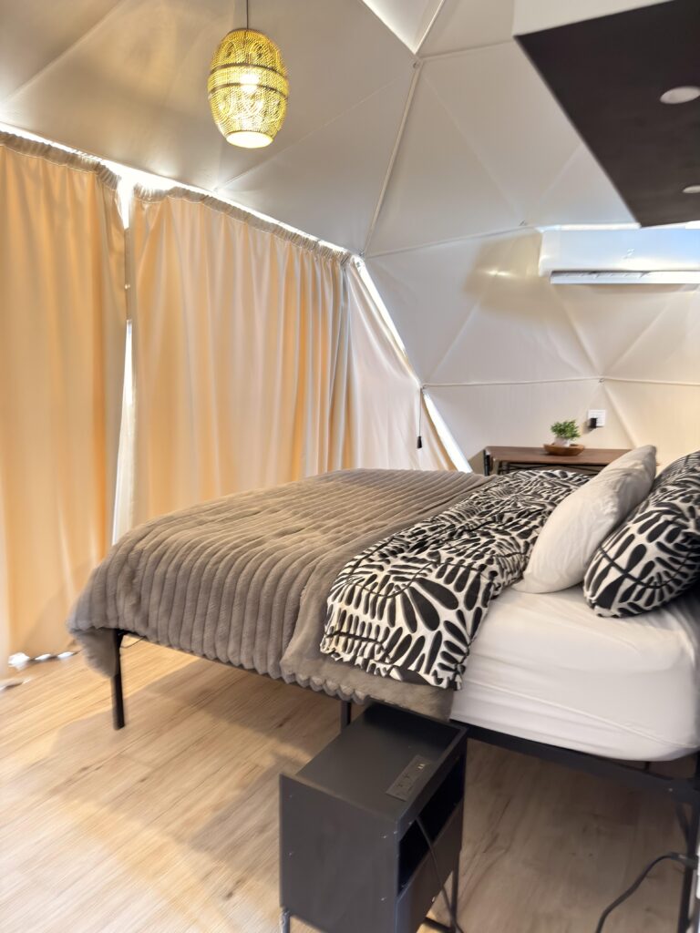 Doppelbett mit gemustertem Kissen und Hängelampe im Glamping-Zelt in Kanab, Utah