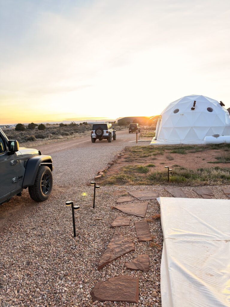 Glamping-Kuppelzelt White Camel in Kanab bei Sonnenuntergang mit parkenden Jeeps