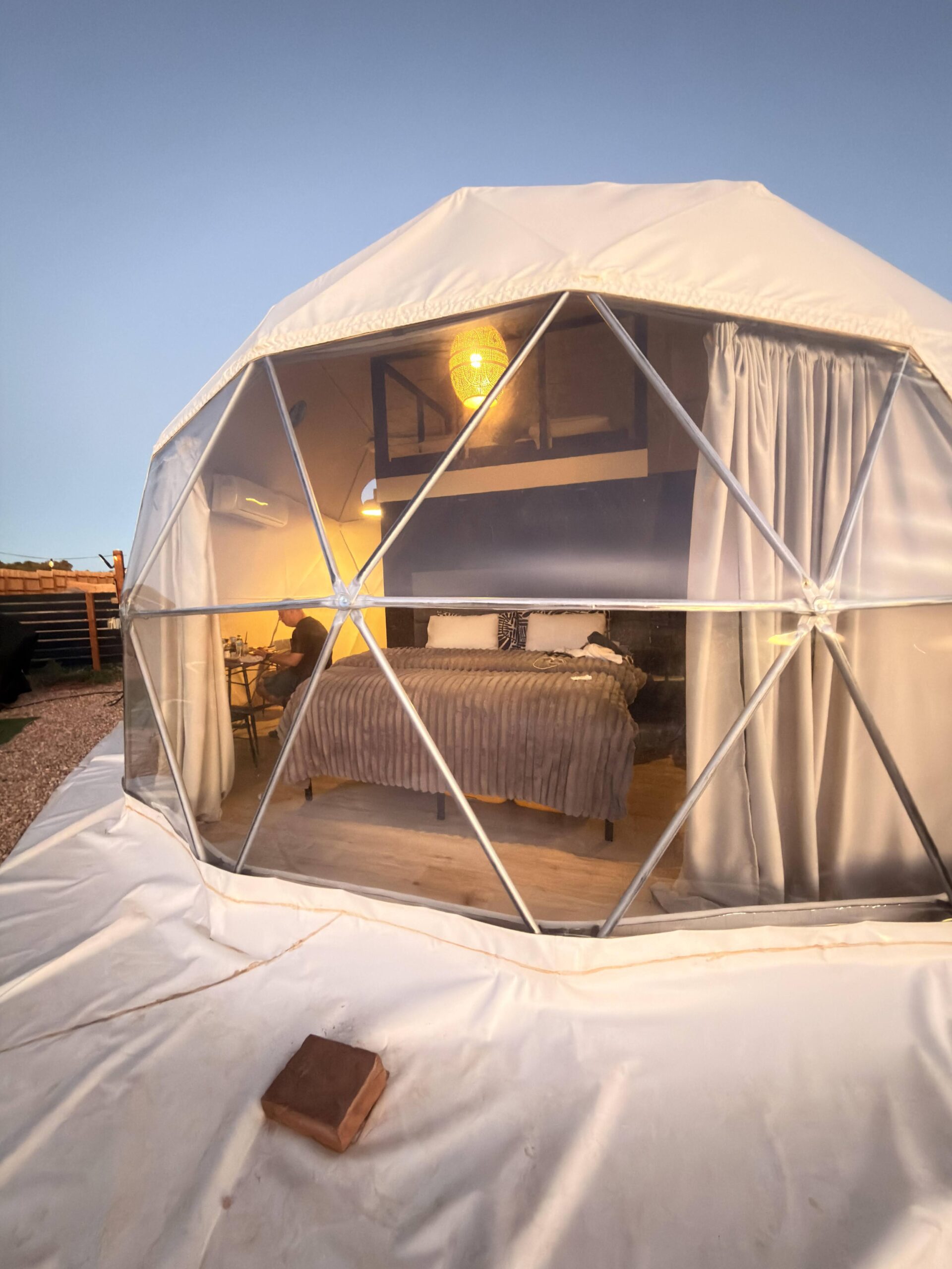 Blick in ein Glamping-Zelt mit Bett und warmem Licht am Abend