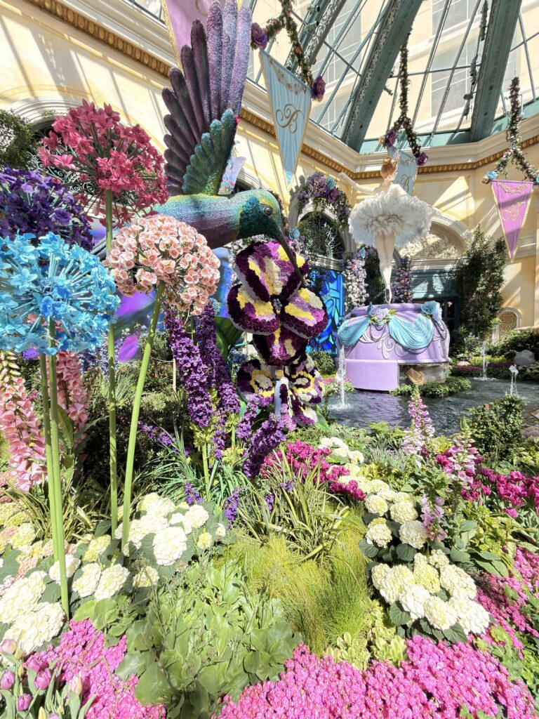 Kolibri-Skulptur zwischen bunten Blumen und Ballerina-Figur im Bellagio Conservatory in Las Vegas
