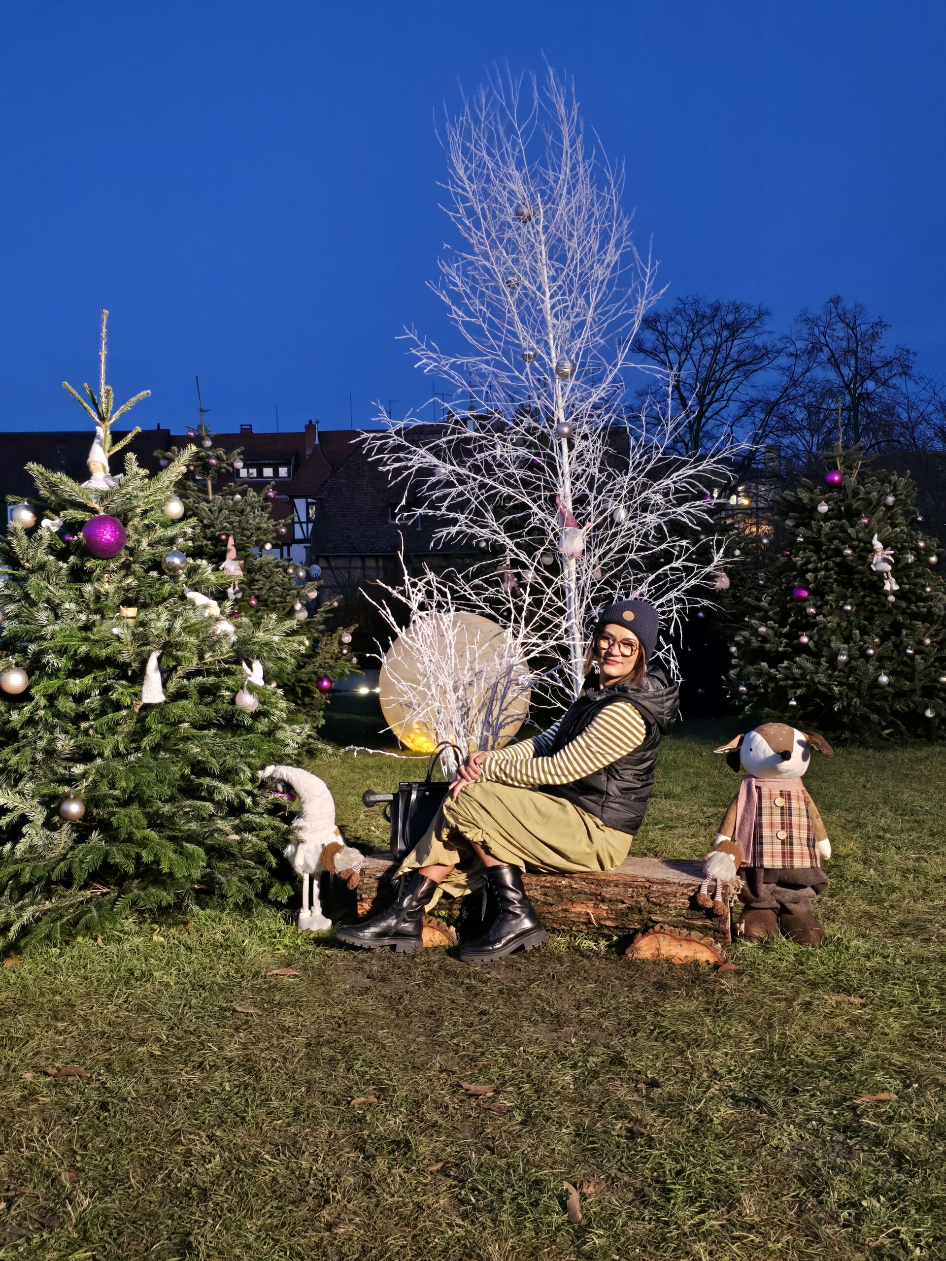 Paar sitzt vor winterlich dekoriertem Baum beim Weihnachtsmarkt Colmar