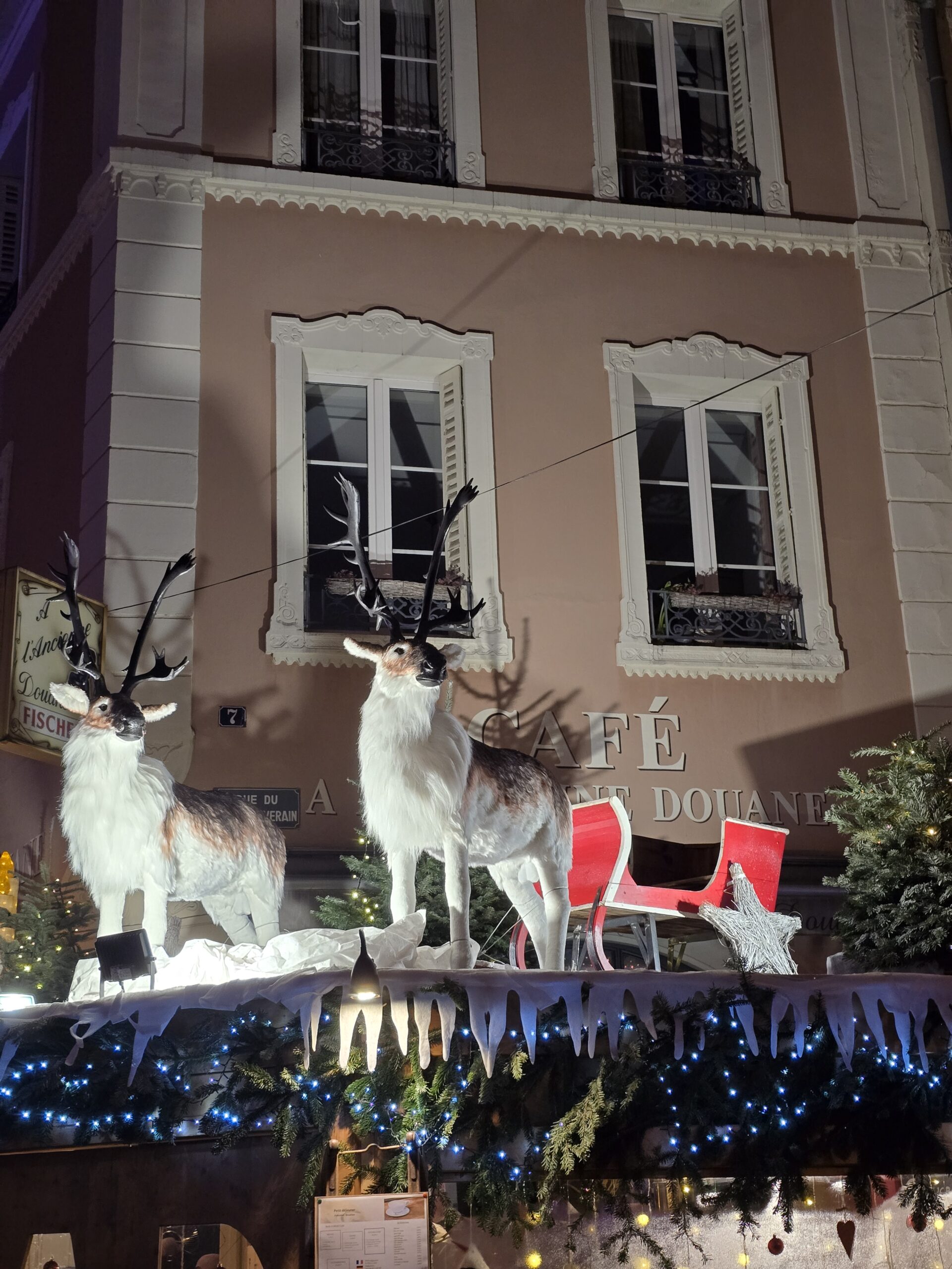 Zwei Rentierfiguren mit Schlitten an der Fassade eines Cafés in Colmar