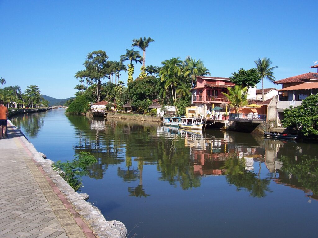 Ruhiger Kanal mit Booten und bunten Kolonialhäusern, gespiegelt im Wasser, Paraty, Brasilien