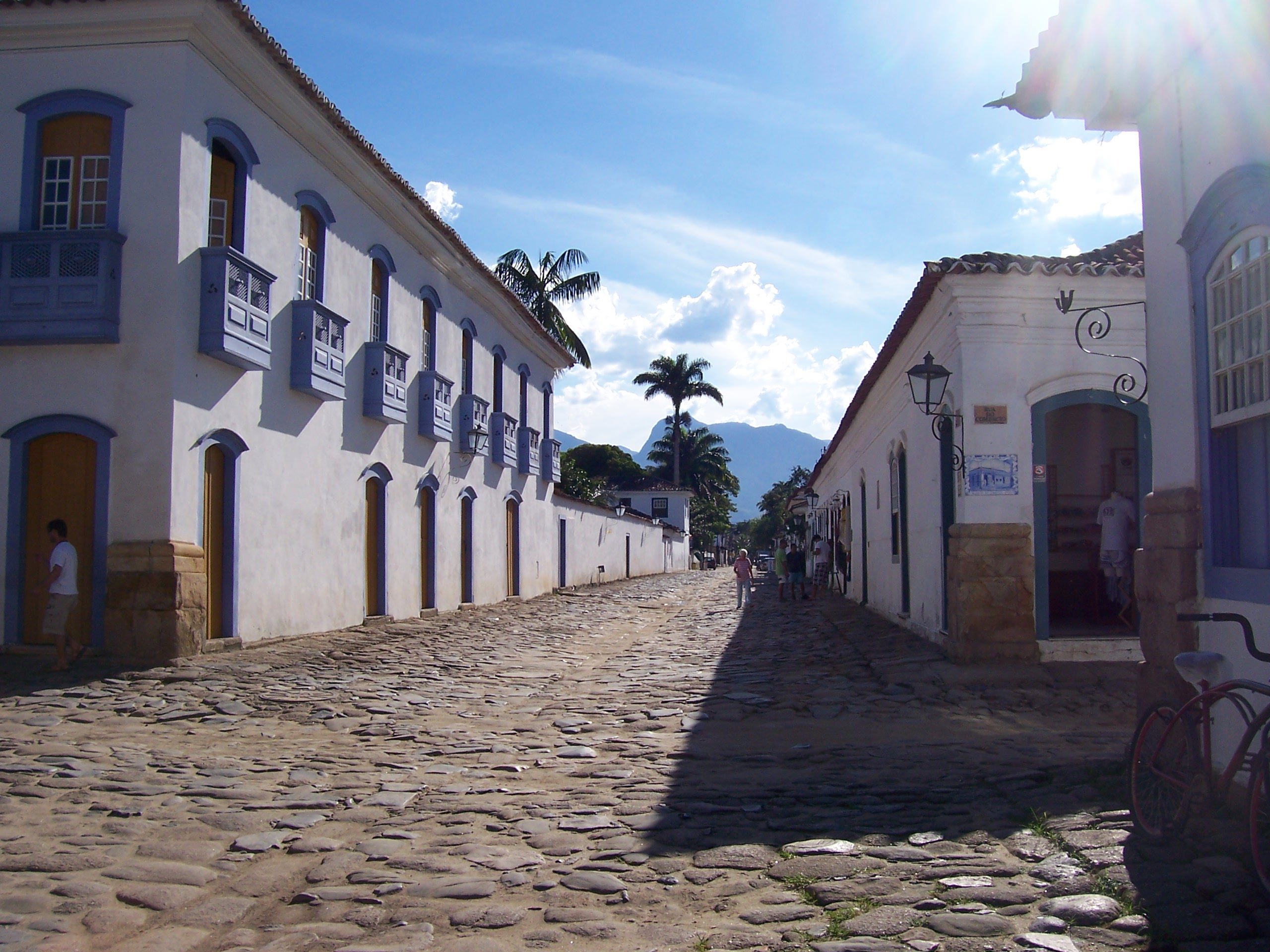 Kopfsteinpflasterstraße zwischen weißen Kolonialhäusern mit blauen Fensterläden im historischen Zentrum von Paraty, Brasilien