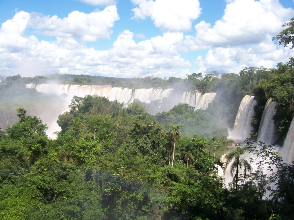 Panoramablick auf eine lange Reihe tosender Wasserfälle umgeben von tropischem Regenwald, Iguaçu-Fälle, Brasilien