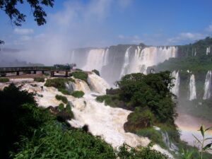 Besuchersteg vor der breiten Fallreihe der Iguaçu-Fälle mit aufsteigender Gischt, Brasilien