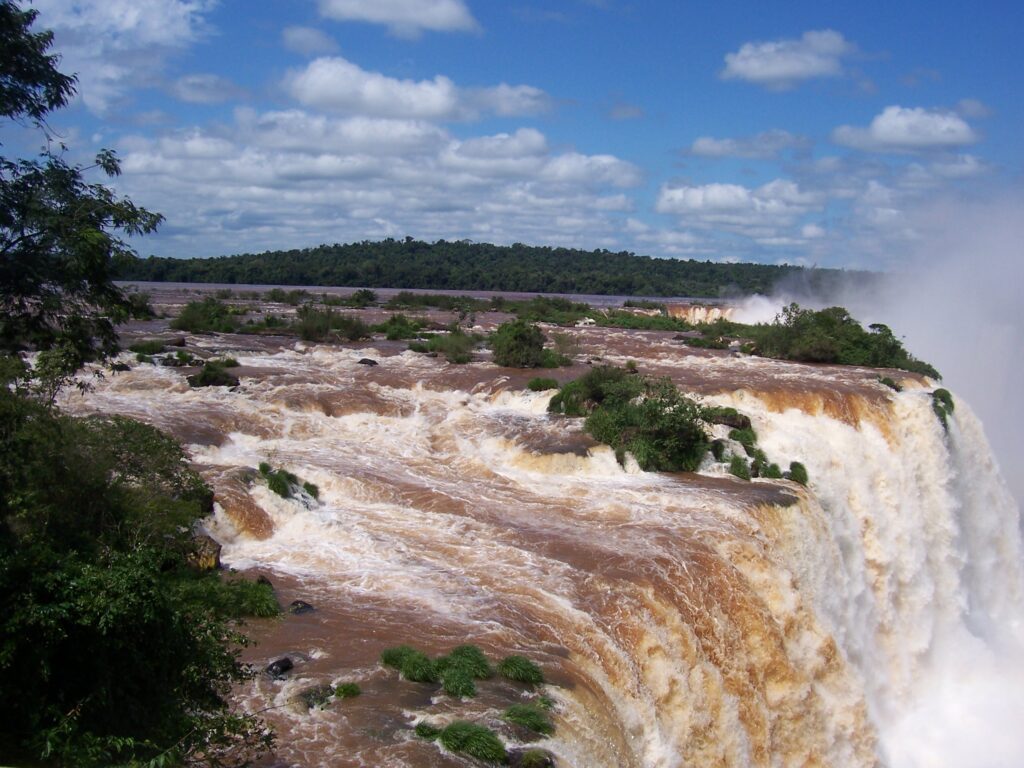 Reißende, lehmfarbene Wassermassen stürzen über die Kante der Iguaçu-Fälle in die Tiefe, Brasilien