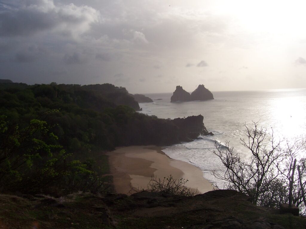 Abenddämmerung über einer Bucht mit den Felsen Dois Irmãos in der Ferne, Fernando de Noronha, Brasilien
