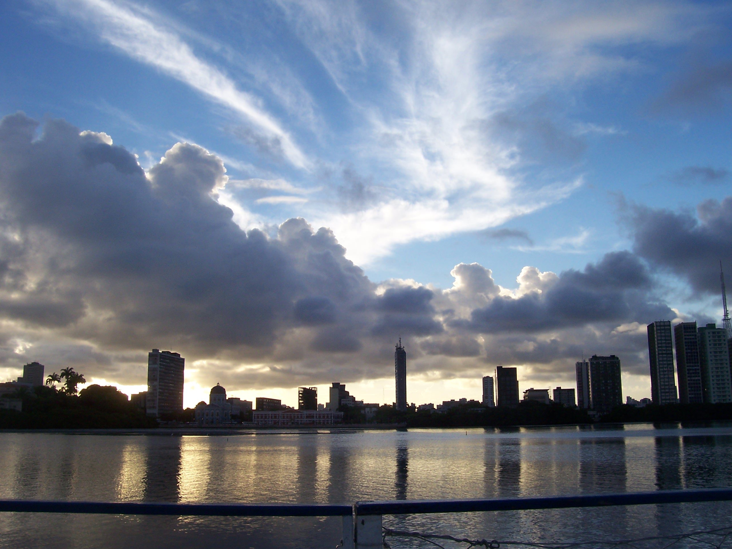 Silhouette der Skyline von Recife mit dramatischem Wolkenhimmel bei Sonnenuntergang, gespiegelt im Fluss, Brasilien