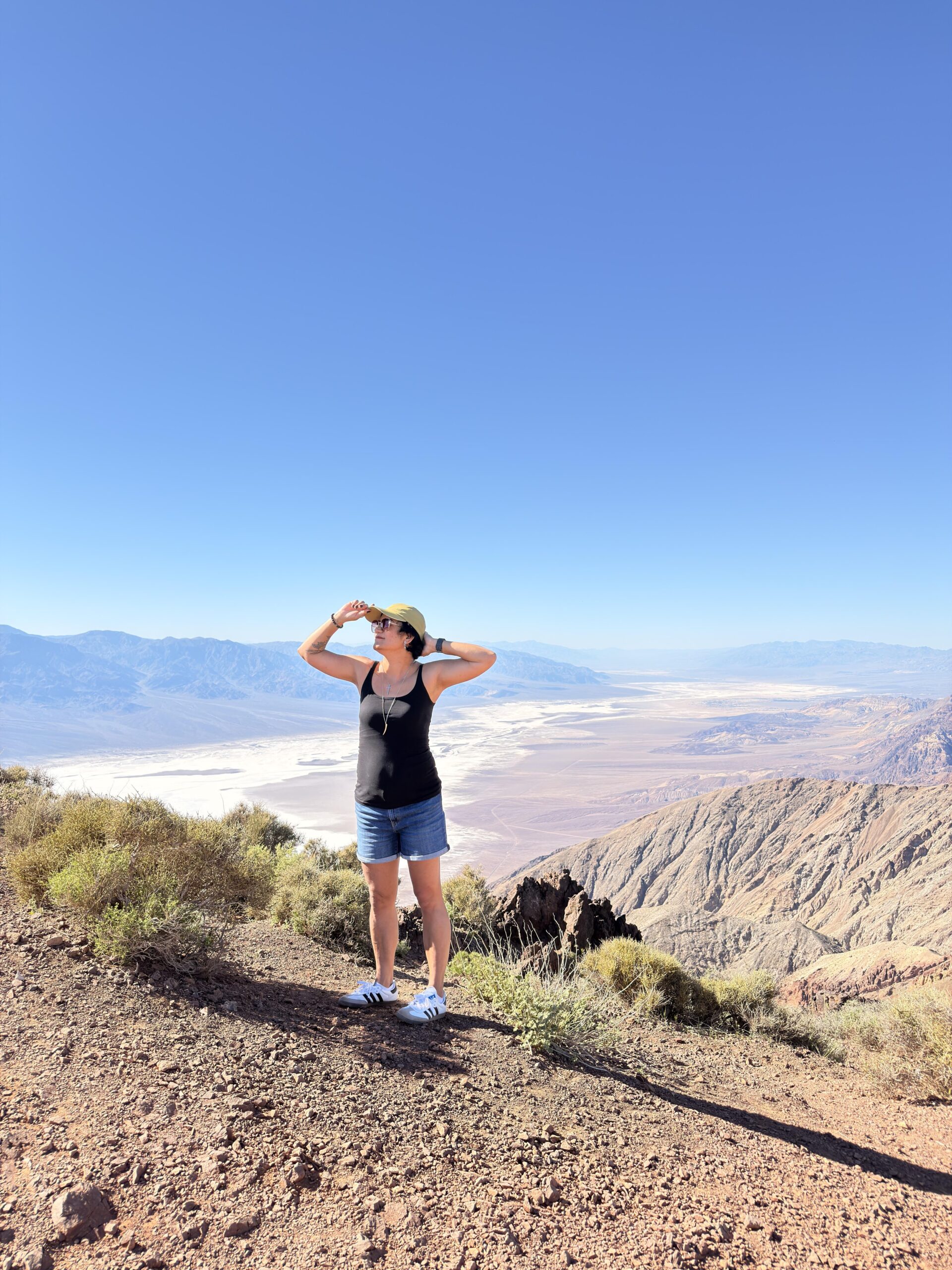 Frau mit Kappe blickt bei Sonnenschein auf die Salzebene des Death Valley vom Dante's View aus