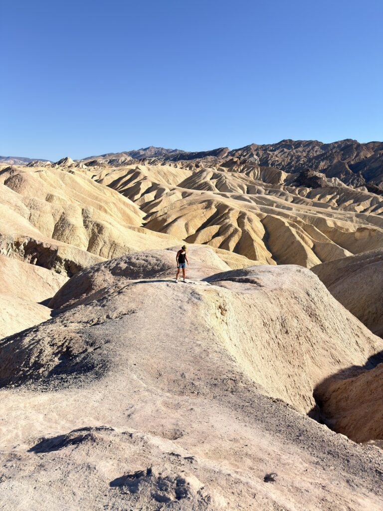 Frau steht auf einem Felsvorsprung inmitten der Badlands von Zabriskie Point