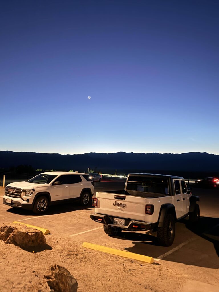 Zwei parkende Fahrzeuge bei Dämmerung mit aufgehendem Mond über Stovepipe Wells