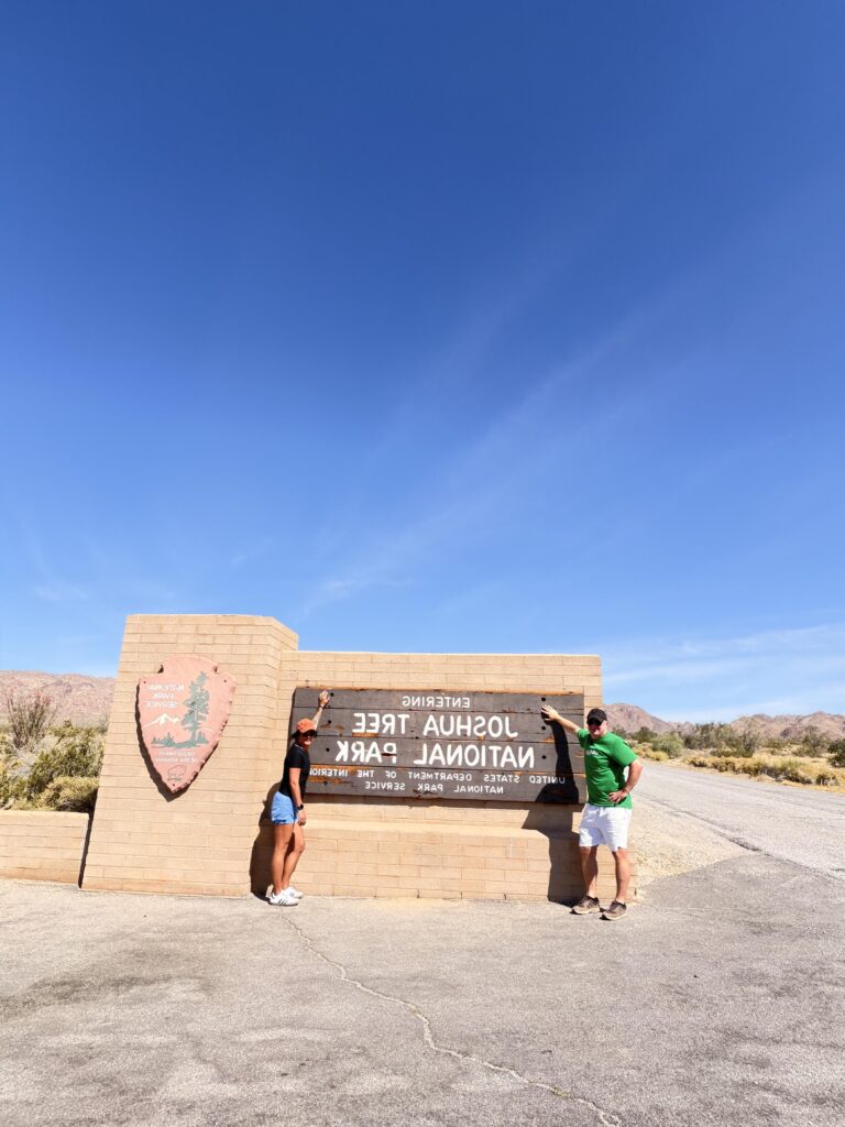 Zwei Personen am Eingangsschild des Joshua Tree National Park