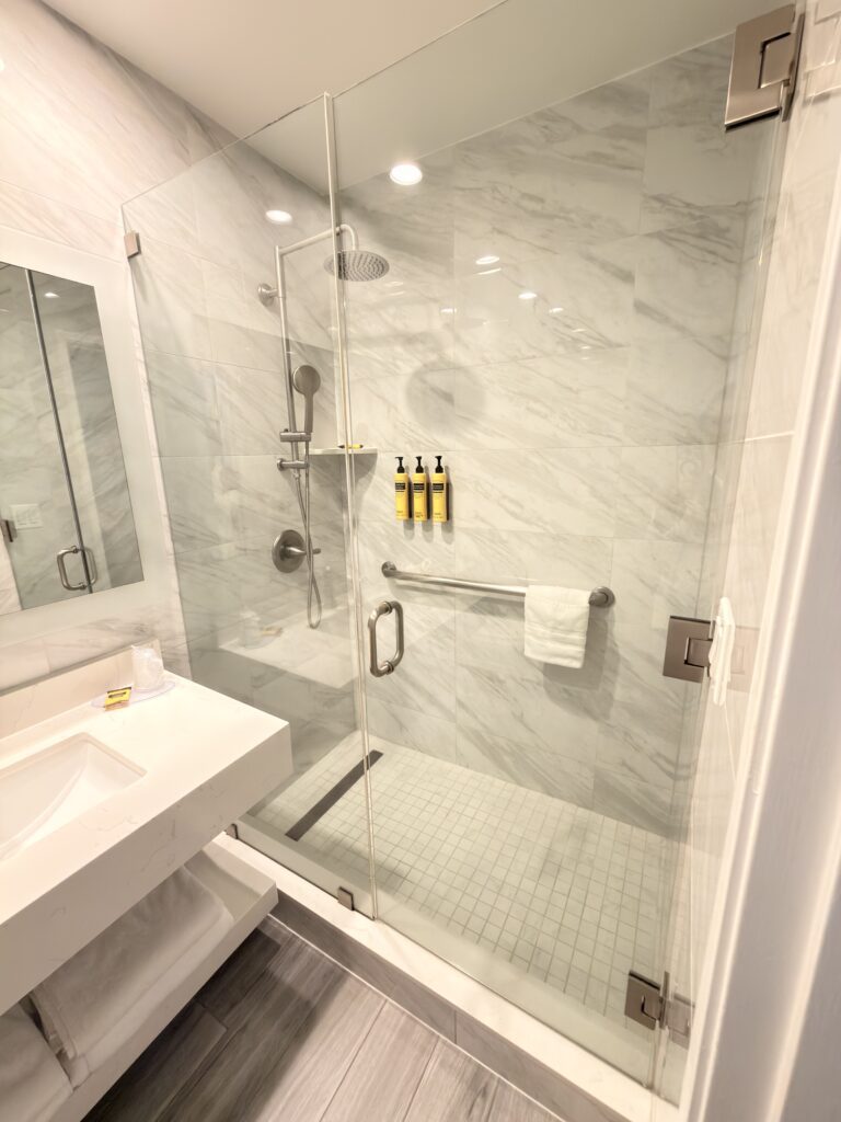 Moderne Duschkabine mit Marmorfliesen und Regendusche im Badezimmer des Hotels