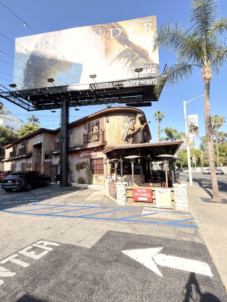 Saddle Ranch Restaurant am Sunset Strip mit Outlander-Werbetafel, gegenüber dem Best Western Sunset Plaza
