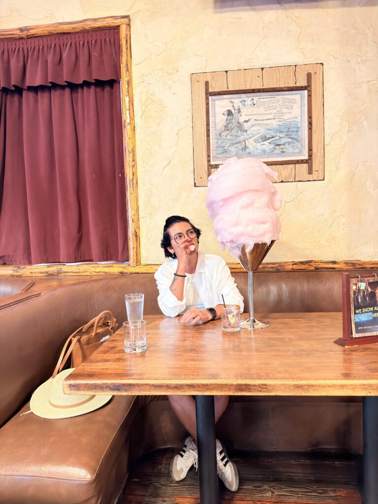 Frau sitzt im Saddle Ranch Restaurant an einem Tisch mit riesiger rosa Zuckerwatte