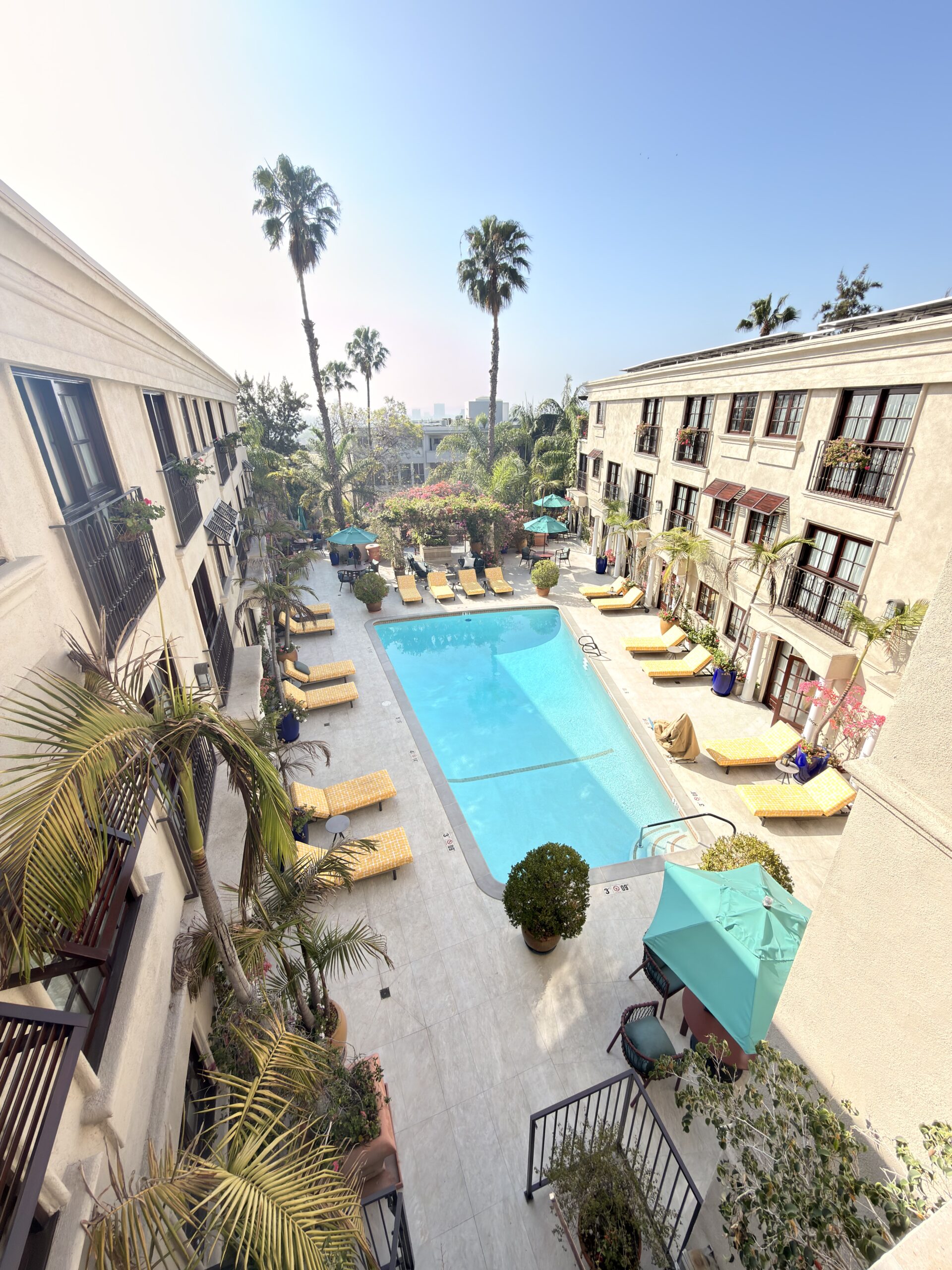 Poolbereich des Best Western Plus Sunset Plaza Hotels mit Liegestühlen und Palmen von oben fotografiert