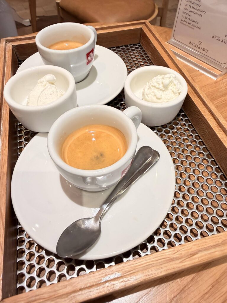 Zwei Espressotassen und zwei Schälchen Vanilleeis auf einem Holztablett in einem Café
