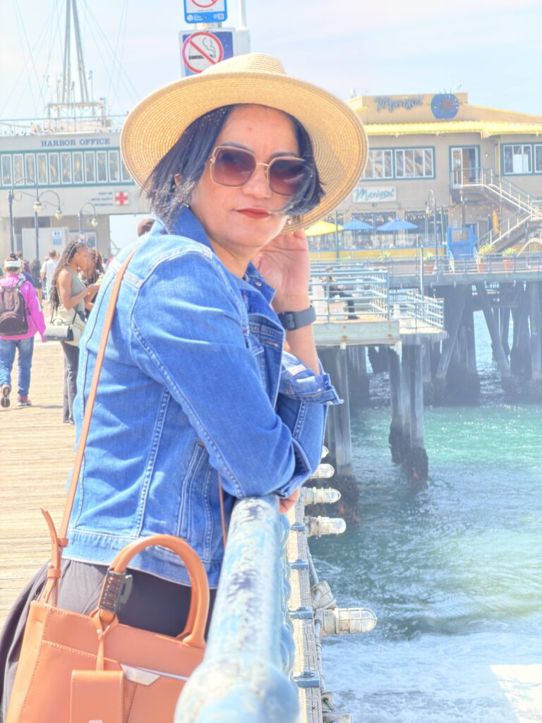 rau mit Strohhut lehnt an einem Geländer am Santa Monica Pier mit Blick auf die Anlegestelle
