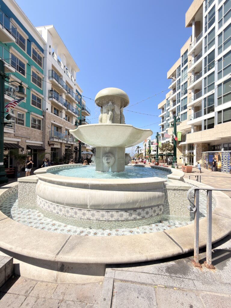 Steinbrunnen mit Löwenkopf-Wasserspeiern zwischen bunten Wohnhäusern in San Diego