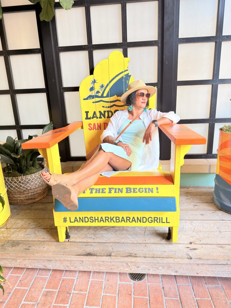 Frau sitzt in einem übergroßen gelben Landshark-Stuhl mit Aufschrift "Let the Fin Begin"