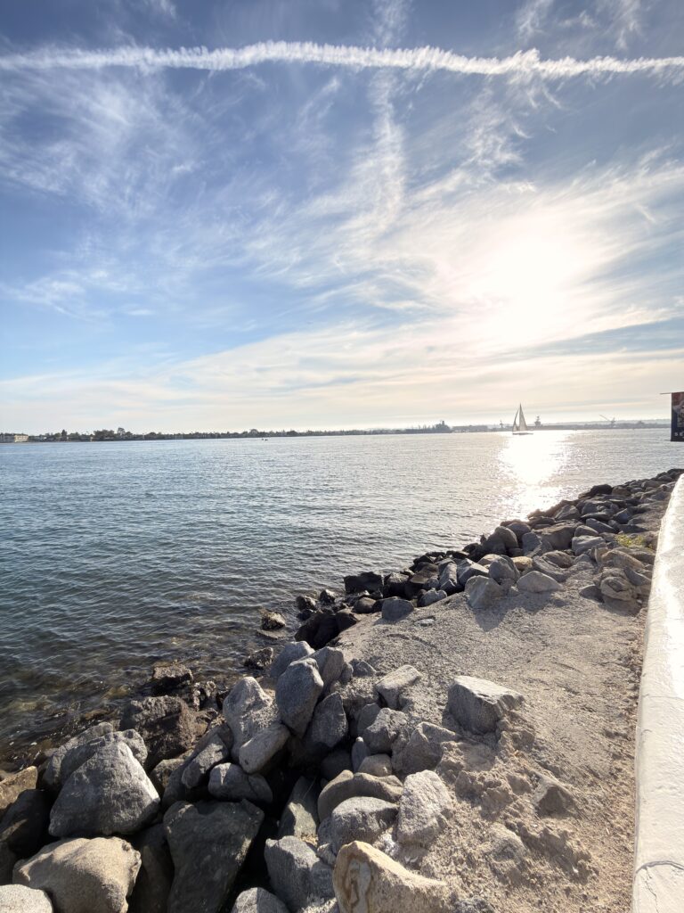 Felsige Küste mit Segelboot in der Bucht von Seaport Village San Diego