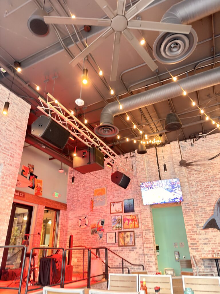 Industrielle Deckengestaltung mit Lichterketten und bunten Postern im Landshark Restaurant