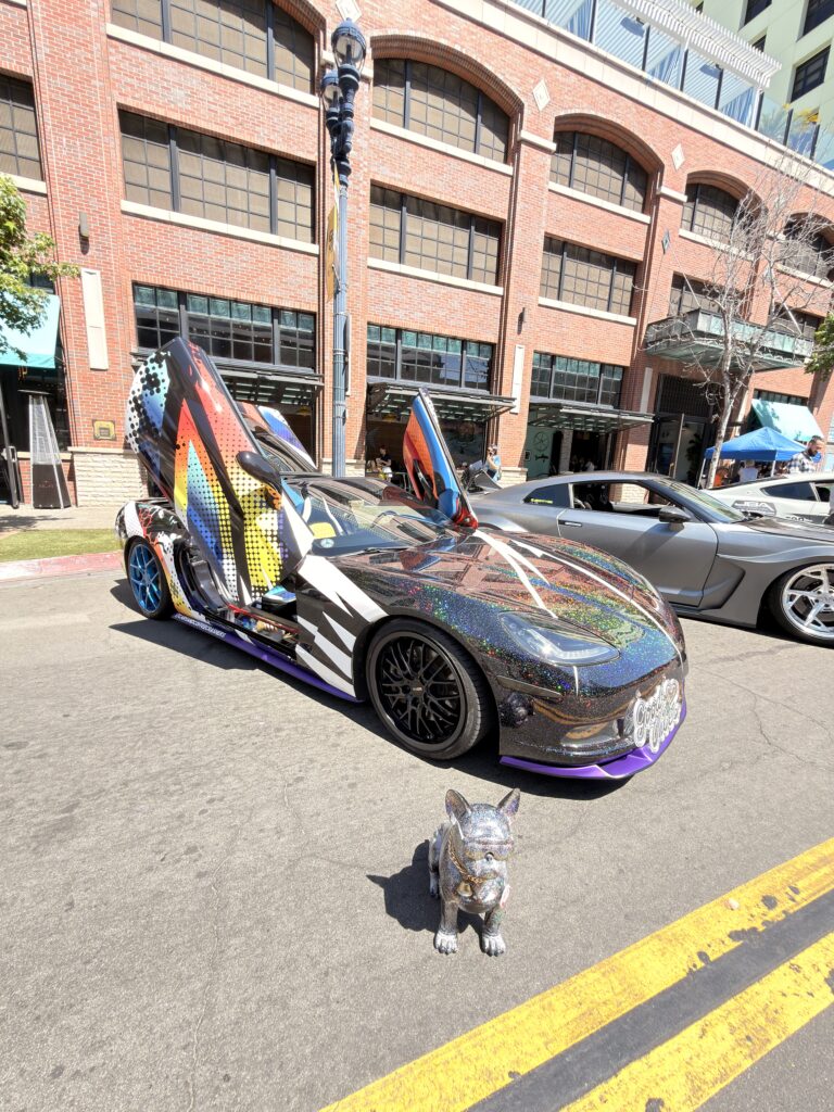 Bunt beklebter Sportwagen mit Flügeltüren und glitzernder Hunde-Skulptur bei Cars & Coffee im Gaslamp Quarter San Diego