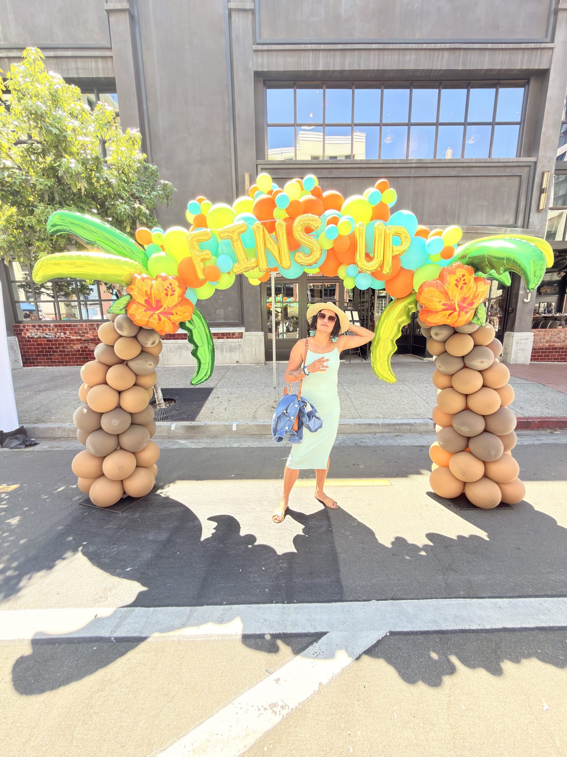 Frau steht unter einem bunten Ballonbogen mit Aufschrift "Fins Up" bei der Saisoneröffnung der San Diego Padres